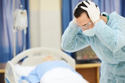 worried doctor leaning over a patient's bed
